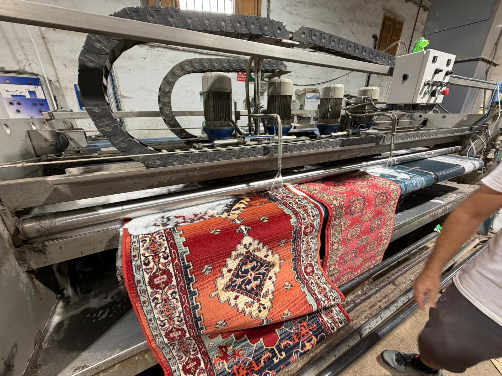 Operario guiando una alfombra en el tren de lavado